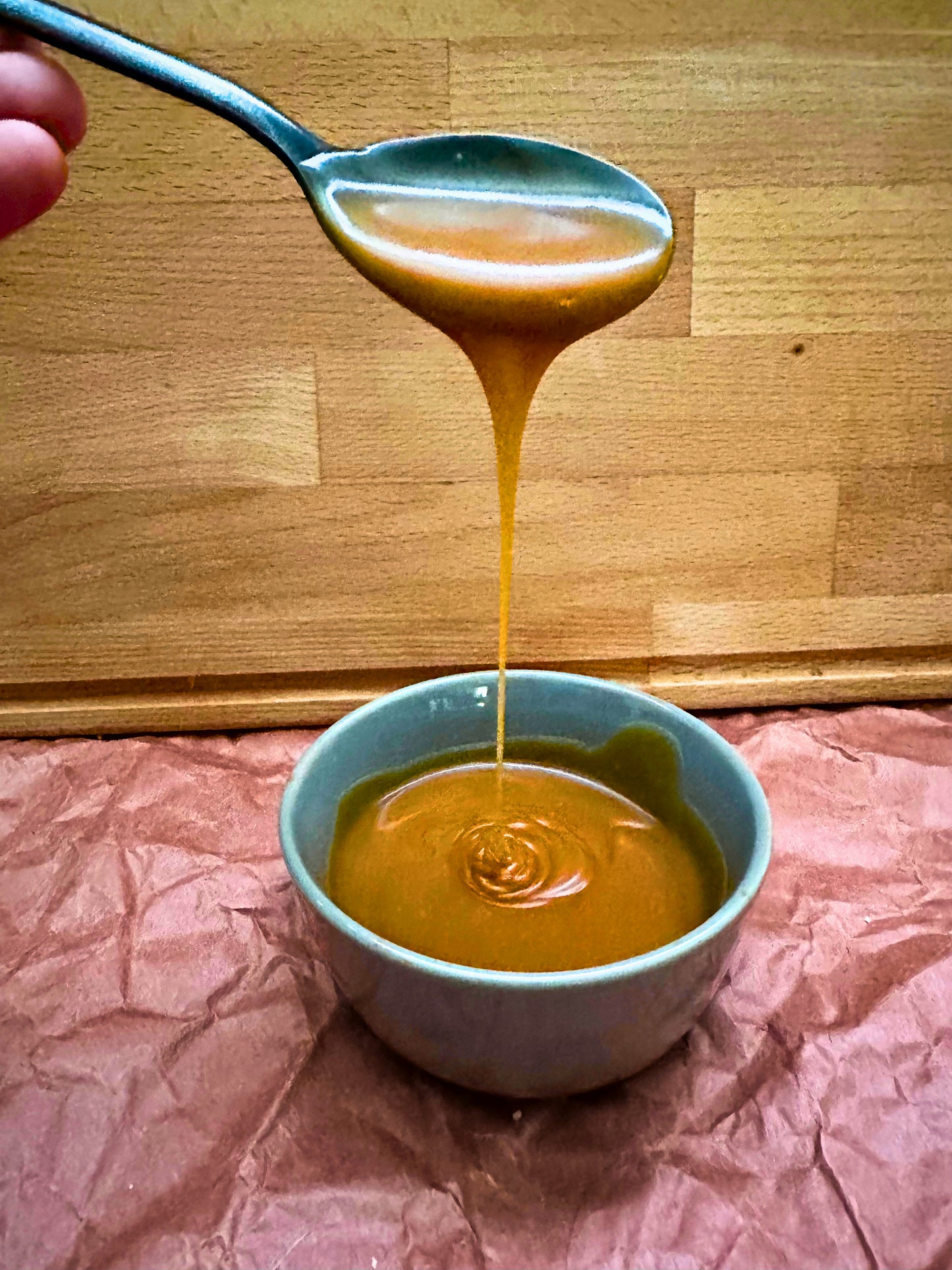 Rich Apple Cinnamon Caramel – Fall Limited Edition drizzling from spoon into bowl, showcasing its smooth texture for dessert or breakfast use.