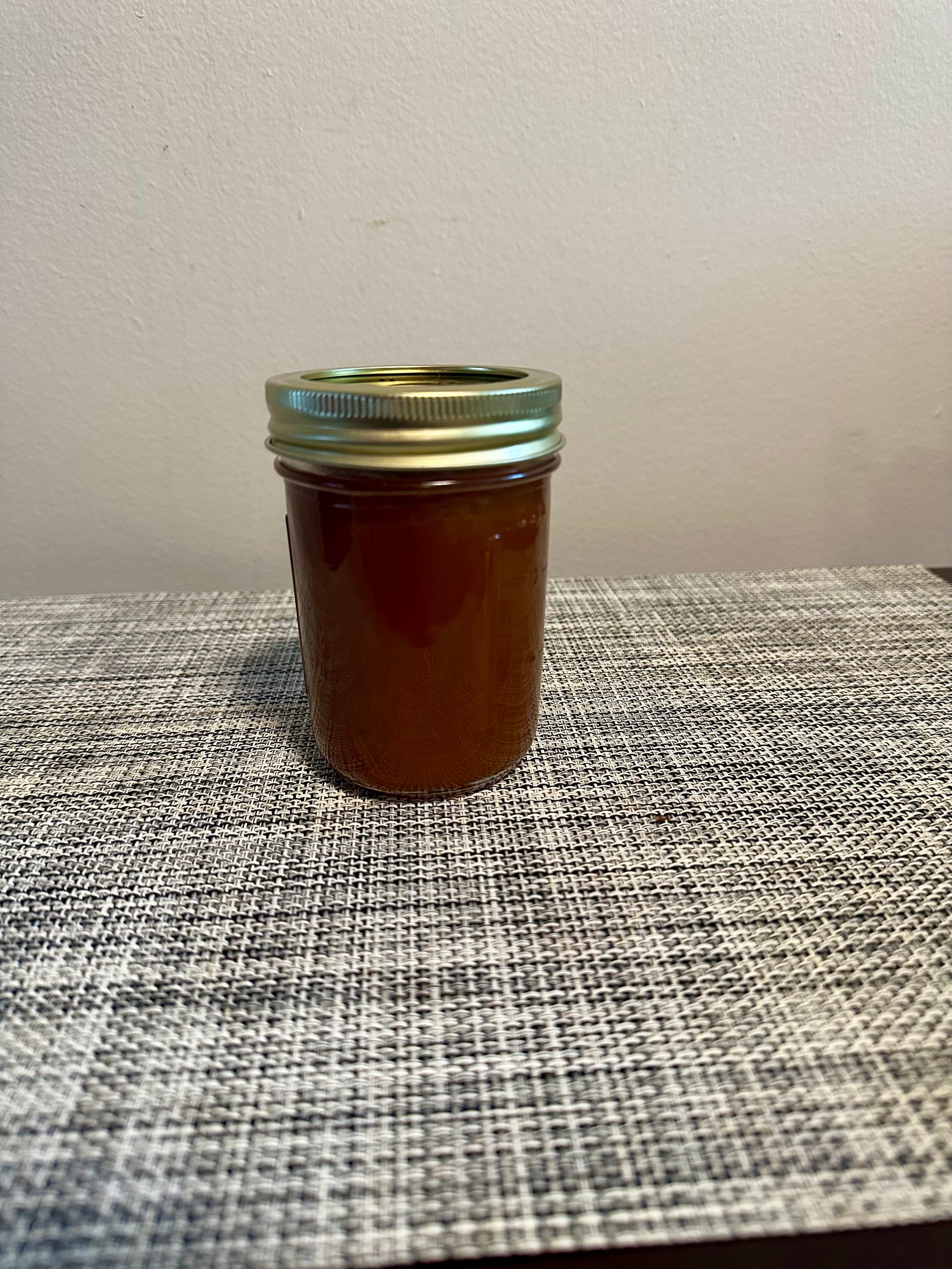 Sealed jar of Small Batch Salted Caramel Sauce on woven placemat, perfect for artisan dessert or caramel coffee syrup use.