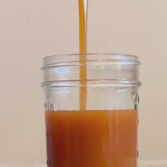 Apple Cinnamon Caramel – Fall Limited Edition being poured into a glass jar, highlighting its golden hue and thick, buttery consistency.